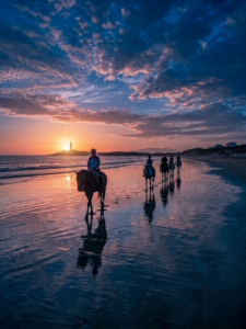 Paseo a caballo por la playa de Zahora al atardecer con el faro de Trafalgar al fondo